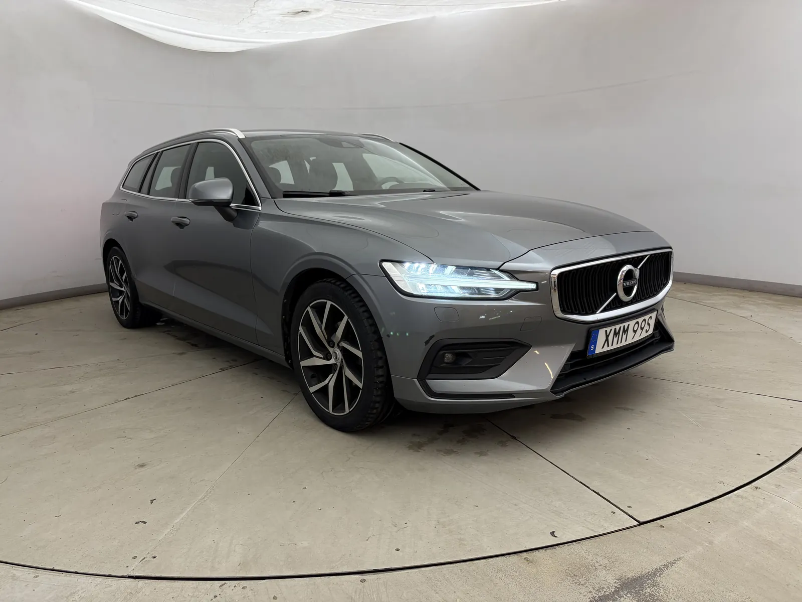 En grå Volvo V60 i en smutsig fotostudio, som bilden togs